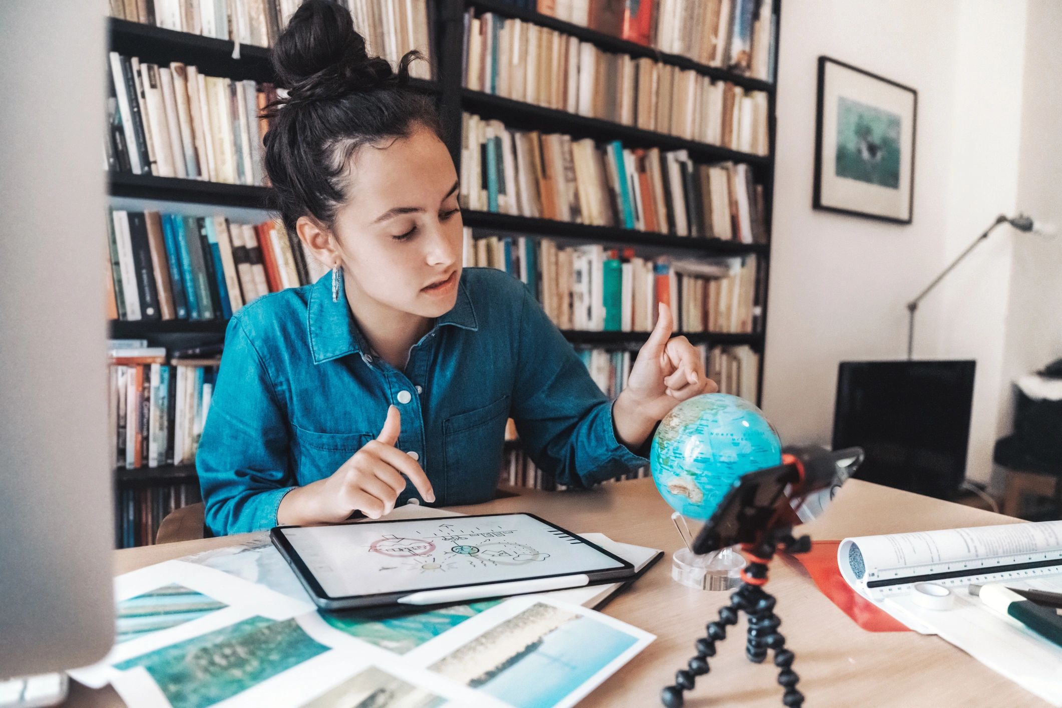 Student studying at desk with tablet and globe
